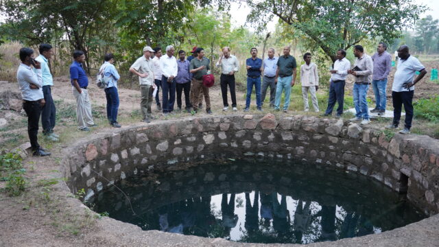 Photo showing people stood around a well full of water